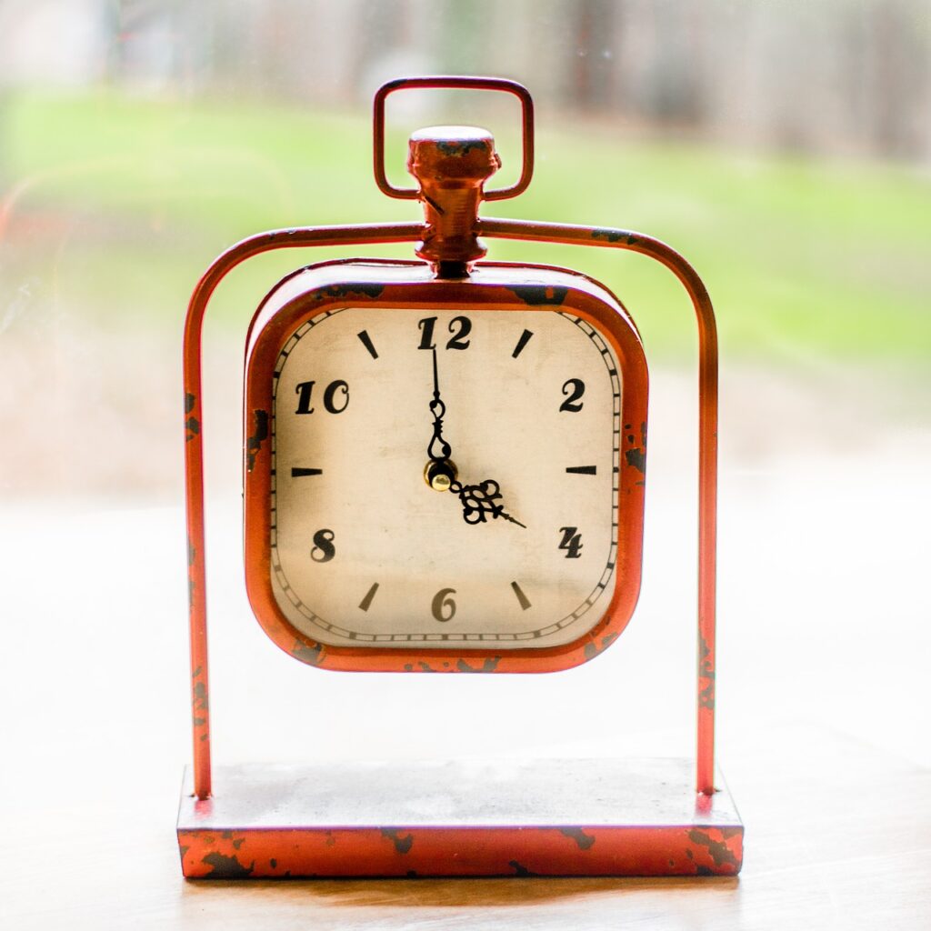 A brown square clock with the time 4 o'clock.