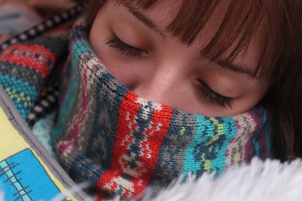 A girl is sleeping with a colorful scarf on her neck