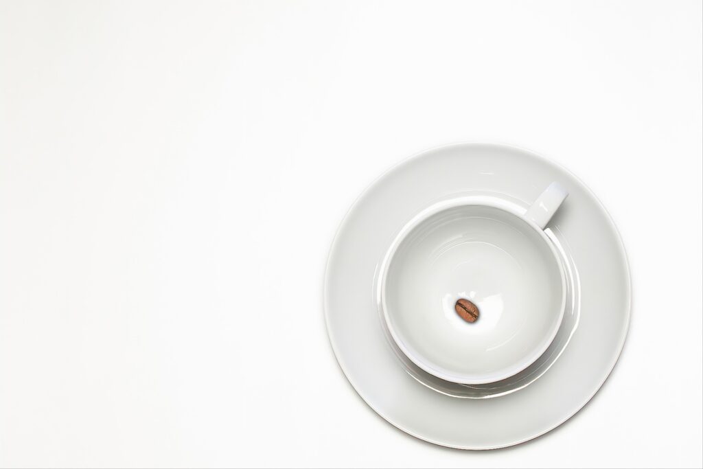 A coffee cup with one coffee bean inside on white background